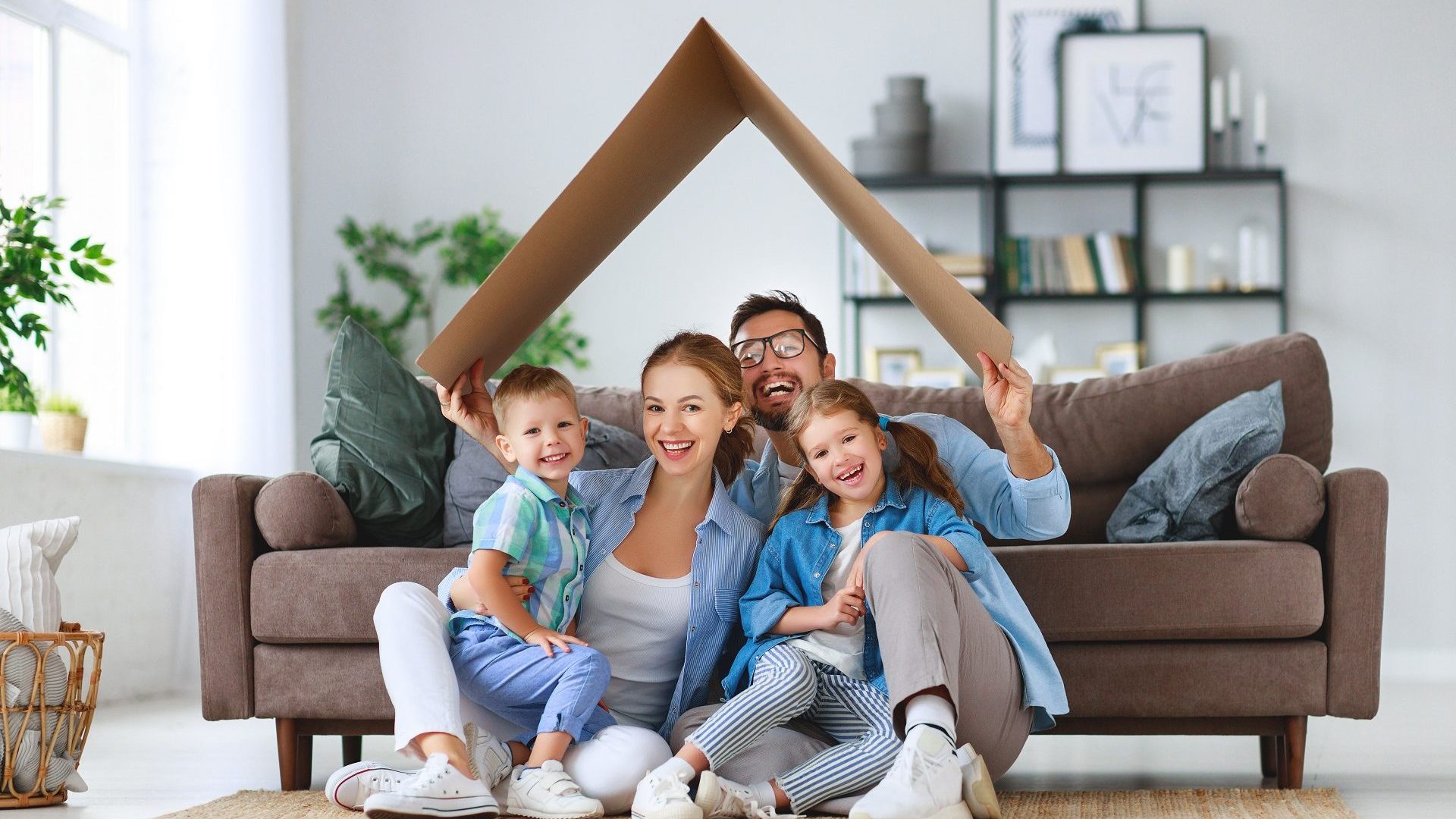 concept of housing and relocation. happy family mother father and kids with roof at home